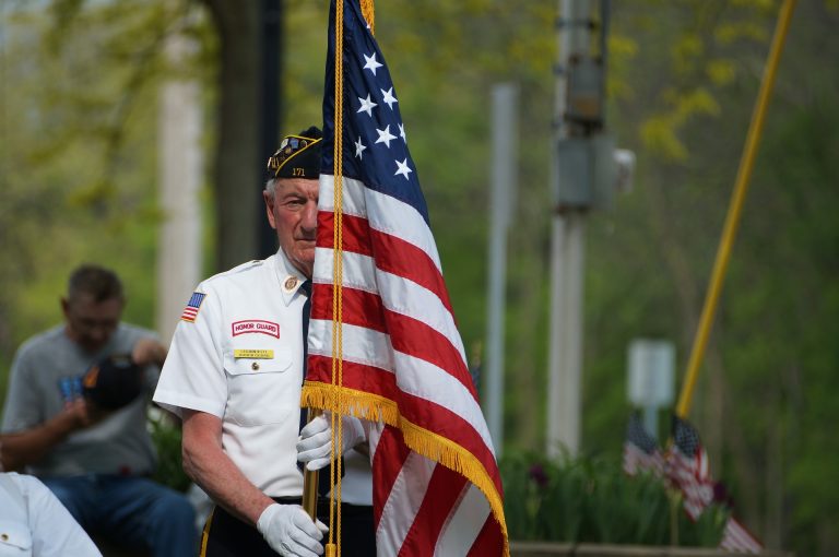Elderly veteran holding American flag in memorial day parade