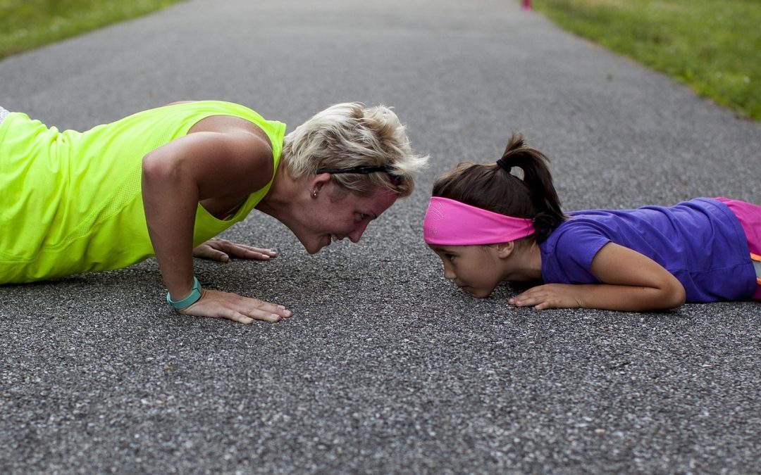 A mom and her young daughter are doing push-ups together as part of their Fitquest fitness quest.
