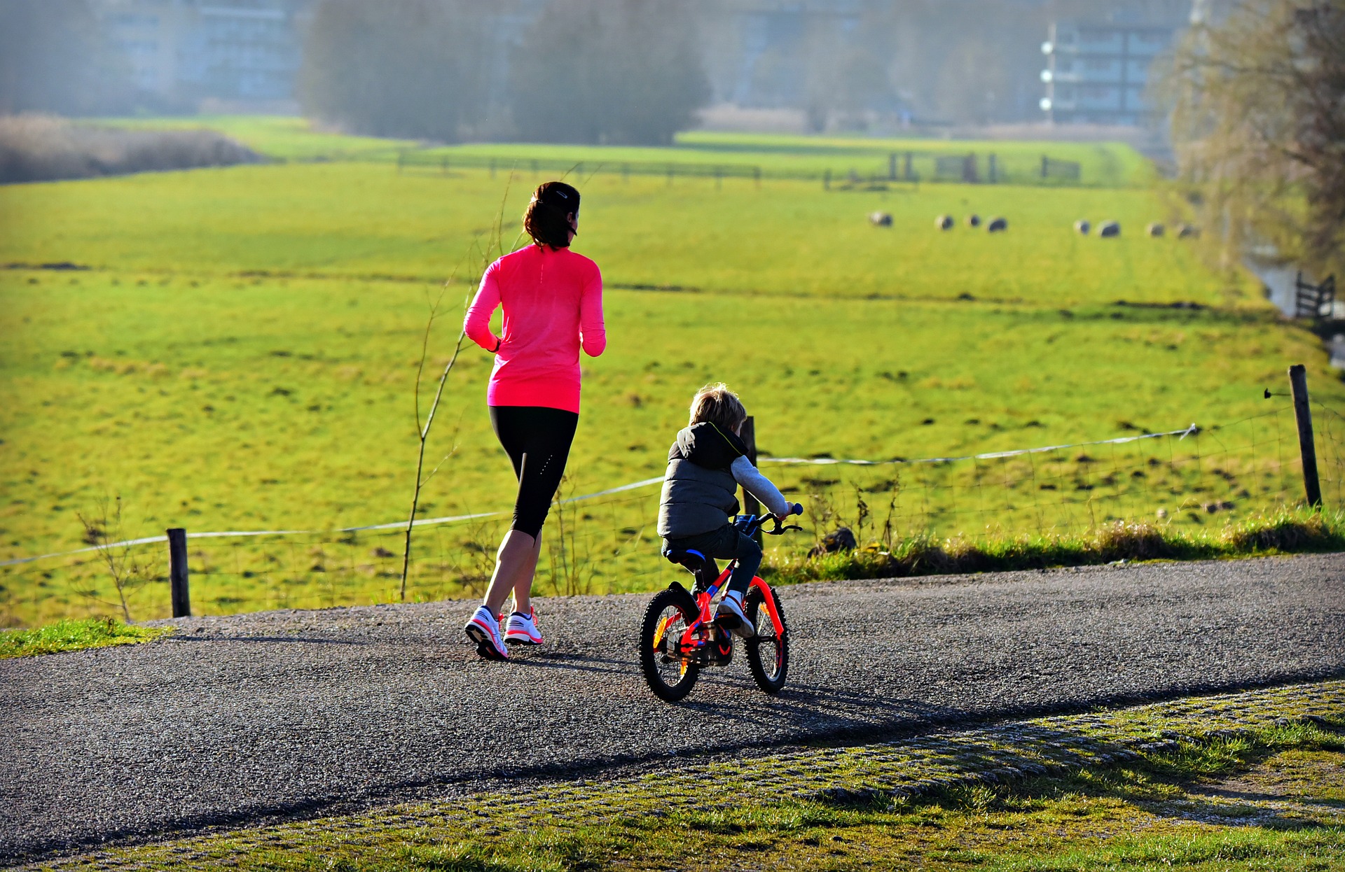 a mom jogging with her daughter while riding a bike