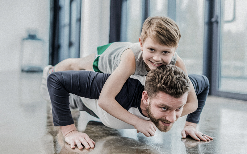 dad doing push ups with son on his back