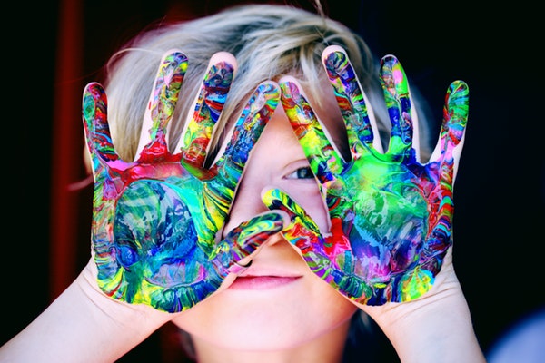 Adorable child with a colorful paint on her palms