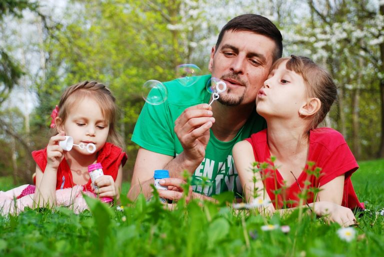 Dad and two girls having fun playing with soap bubbles.